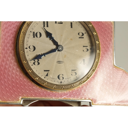 962 - AN ART DECO SILVER AND GUILLOCHE ENAMEL STRUT CLOCK the shaped case with an engraved gilt circular b... 