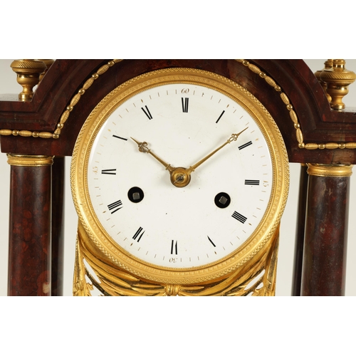 974 - AN EARLY 19TH CENTURY FRENCH ROUGE MARBLE AND ORMOLU PORTICO MANTEL CLOCK the break arched top surmo... 