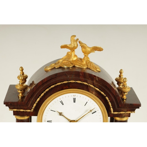 974 - AN EARLY 19TH CENTURY FRENCH ROUGE MARBLE AND ORMOLU PORTICO MANTEL CLOCK the break arched top surmo... 