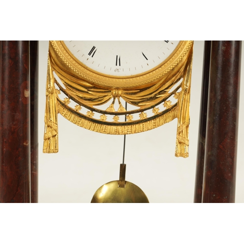 974 - AN EARLY 19TH CENTURY FRENCH ROUGE MARBLE AND ORMOLU PORTICO MANTEL CLOCK the break arched top surmo... 