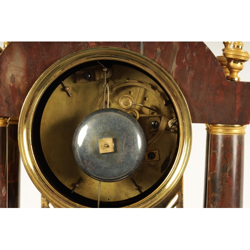 974 - AN EARLY 19TH CENTURY FRENCH ROUGE MARBLE AND ORMOLU PORTICO MANTEL CLOCK the break arched top surmo... 