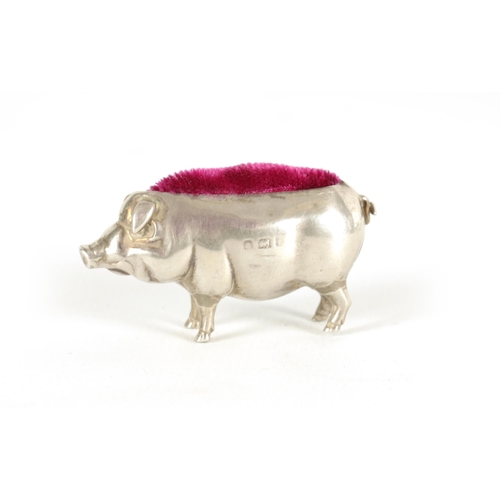 361 - A SMALL EDWARDIAN SILVER PIN CUSHION IN THE FORM OF A PIG depicted in a standing pose with a red cus... 