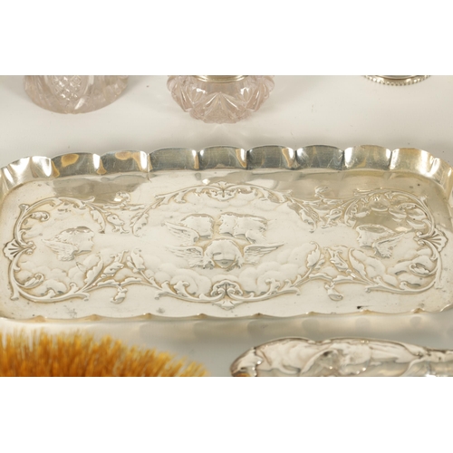 366 - AN ART NOVEAU SILVER NINE PIECE DRESSING TABLE SET decorated with winged chuerbs hallmarked William ... 