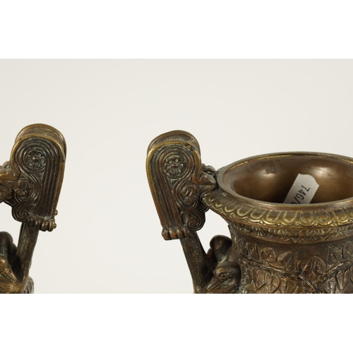 752 - A PAIR OF 19TH CENTURY FRENCH BRONZE ROMANESQUE TWO-HANDLED URNS on stepped black slate bases. (29cm... 