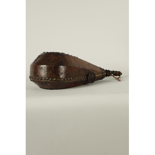 788 - A 19TH CENTURY LEATHER AND BRASS STUDDED HARVEST FLASK of rounded tapering faceted form with fleur d... 