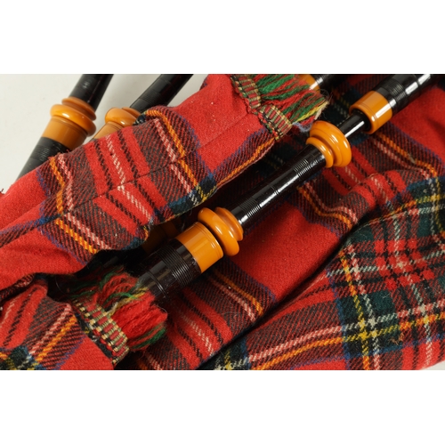 128 - A SET OF SCOTTISH BAGPIPES having a tartan covered bag and turned wooden pipes