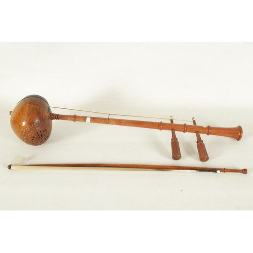 71 - A SAW U THAI FIDDLE WITH BOW Having a knopped turned rosewood neck with two tuning pegs and coconut ... 