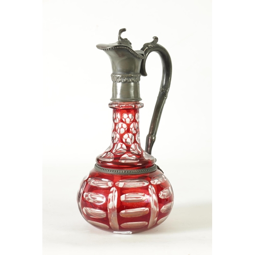 24 - A 19TH CENTURY BOHEMIAN GLASS CLARET JUG of cut red glass overlay design with pewter mounts. (27cm h... 