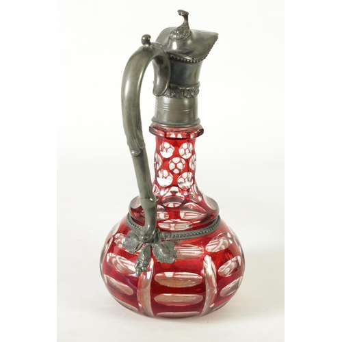 24 - A 19TH CENTURY BOHEMIAN GLASS CLARET JUG of cut red glass overlay design with pewter mounts. (27cm h... 
