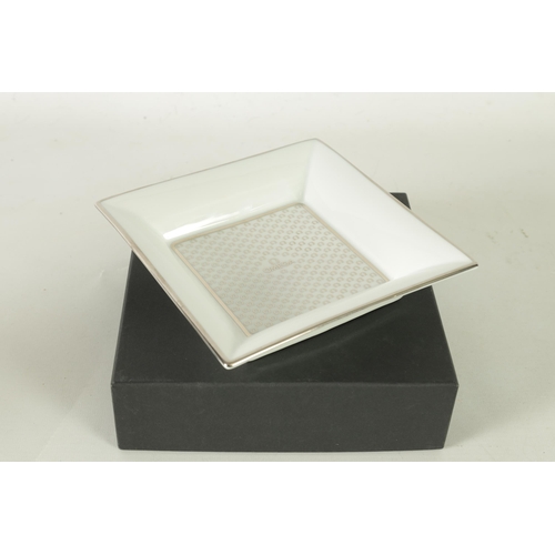 84 - A 1960’S BOXED OMEGA LIMOGES PORCELAIN OMEGA TRINKET DISH of square form with silver motif decoratio... 