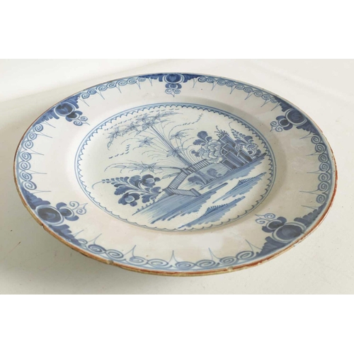 55 - AN 18TH-CENTURY DELFT BLUE AND WHITE PLATE with scrolled spired border enclosing a formal fenced gar... 
