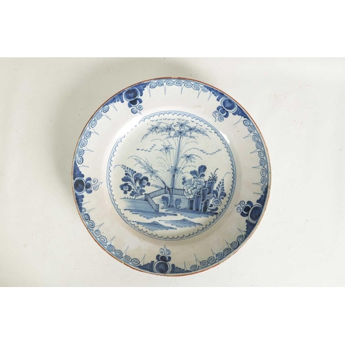 55 - AN 18TH-CENTURY DELFT BLUE AND WHITE PLATE with scrolled spired border enclosing a formal fenced gar... 