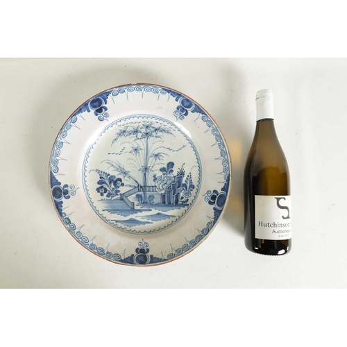 55 - AN 18TH-CENTURY DELFT BLUE AND WHITE PLATE with scrolled spired border enclosing a formal fenced gar... 