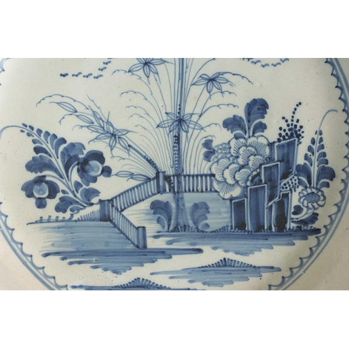 55 - AN 18TH-CENTURY DELFT BLUE AND WHITE PLATE with scrolled spired border enclosing a formal fenced gar... 