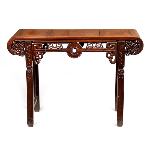 125 - A 19TH CENTURY CHINESE HARDWOOD ALTAR TABLE with panelled top and scrolled carved sides joined by a ... 