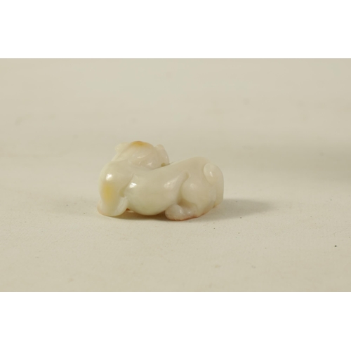 133 - A CHINESE WHITE JADE SCULPTURE modelled as a recumbent lion with russet inclusions to the top of the... 