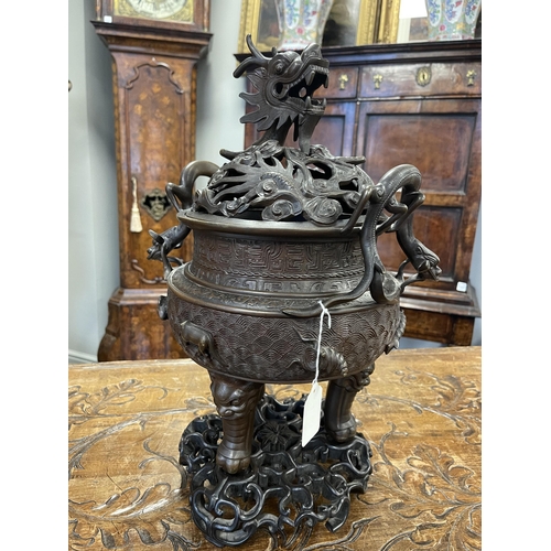 156 - A 19TH CENTURY CHINESE BRONZE CENSER AND LID MOUNTED ON A HARDWOOD STAND with pierced dragons head a... 