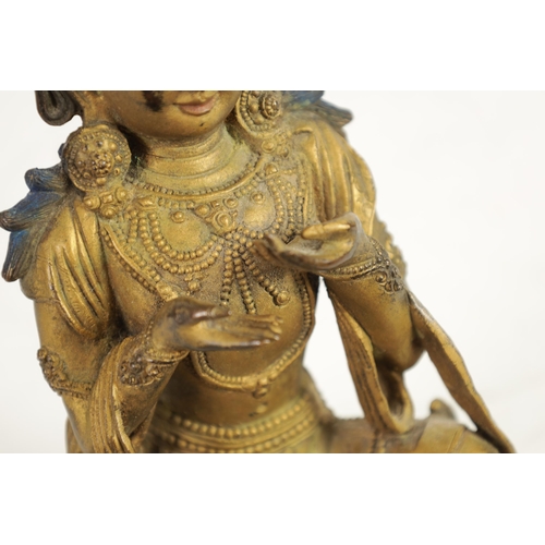 164 - AN EARLY GILT BRONZE TIBETAN BUDDHA highlighted in blue and mounted on a circular bronze moulded bas... 