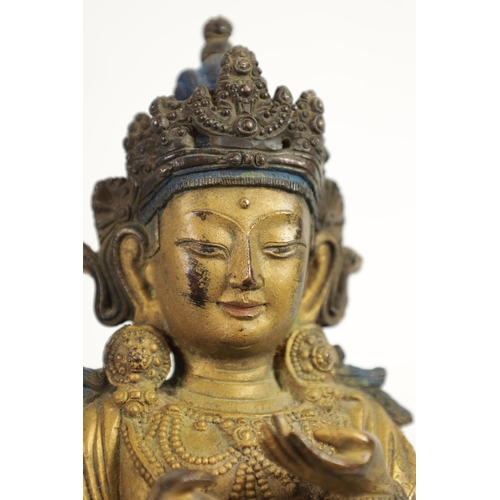 164 - AN EARLY GILT BRONZE TIBETAN BUDDHA highlighted in blue and mounted on a circular bronze moulded bas... 