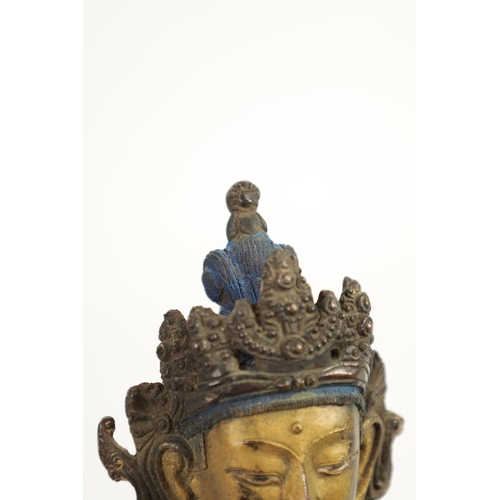 164 - AN EARLY GILT BRONZE TIBETAN BUDDHA highlighted in blue and mounted on a circular bronze moulded bas... 