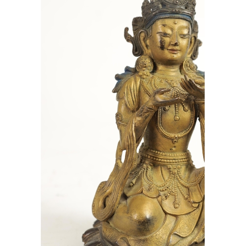 164 - AN EARLY GILT BRONZE TIBETAN BUDDHA highlighted in blue and mounted on a circular bronze moulded bas... 