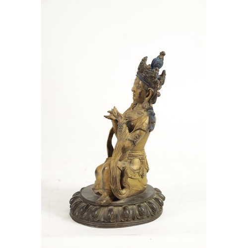 164 - AN EARLY GILT BRONZE TIBETAN BUDDHA highlighted in blue and mounted on a circular bronze moulded bas... 