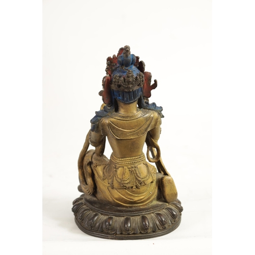 164 - AN EARLY GILT BRONZE TIBETAN BUDDHA highlighted in blue and mounted on a circular bronze moulded bas... 