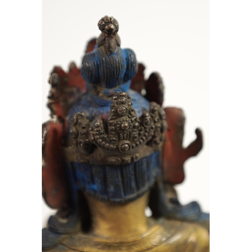 164 - AN EARLY GILT BRONZE TIBETAN BUDDHA highlighted in blue and mounted on a circular bronze moulded bas... 