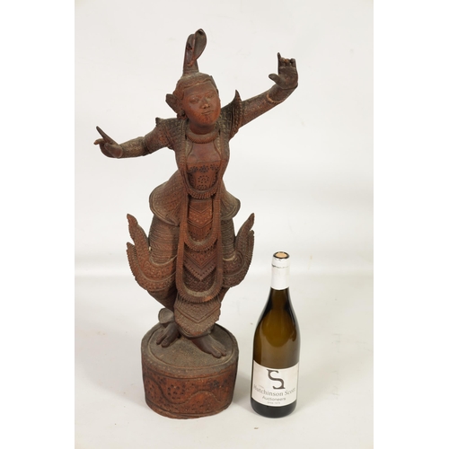 193 - AN EARLY 20TH CENTURY BURMESE CARVED HARDWOOD DANCING FIGURE mouted on a wavy edge base (68cm high )