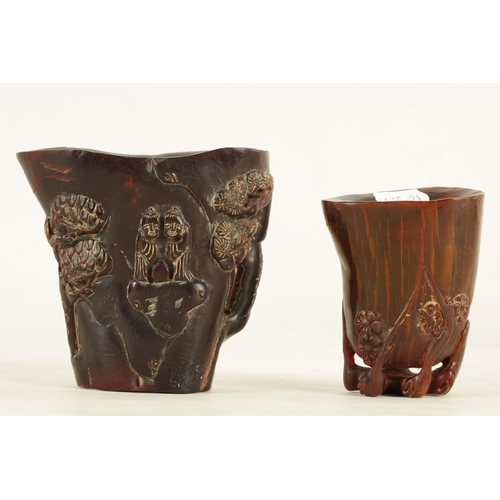 194 - TWO CHINESE CARVED HORN LIBATION CUPS the larger decorated with blossoming trees and figures, four-c... 