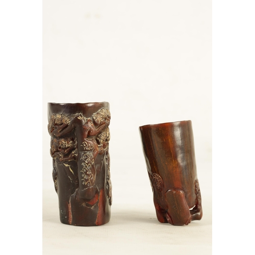 194 - TWO CHINESE CARVED HORN LIBATION CUPS the larger decorated with blossoming trees and figures, four-c... 