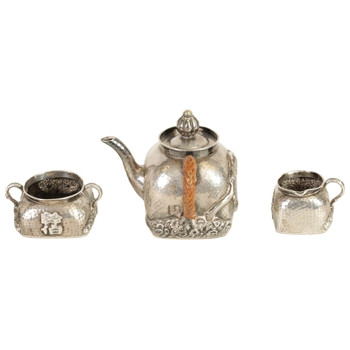 253 - AN EARLY 20TH CENTURY CHINESE SILVER THREE PIECE TEA SET of square form and planished design decorat... 