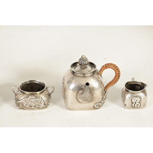 253 - AN EARLY 20TH CENTURY CHINESE SILVER THREE PIECE TEA SET of square form and planished design decorat... 