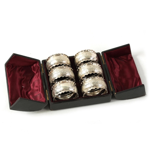 298 - A CASED SET OF SIX VICTORIAN SILVER SERVIETTE RINGS with engraved foliated bands within crimped bord... 