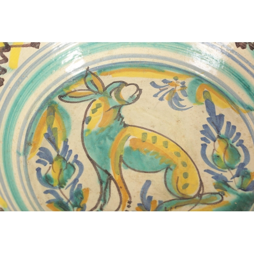 31 - AN EARLY SPANISH LEBRILLO CERAMIC CHARGER with polychrome coloured decoration depicting a dog to the... 