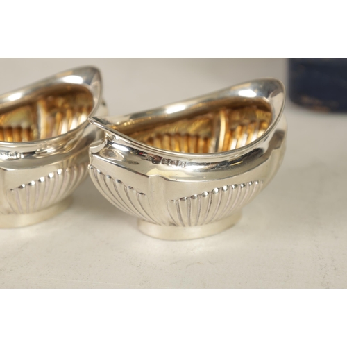 321 - AN EDWARD VII CASED SET OF FOUR SILVER OPEN SALTS AND SPOONS the oval boat-shaped bodies with gilt i... 