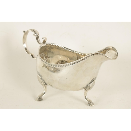 345 - A GEORGE III IRISH SILVER SAUCE BOAT with leaf-capped scroll handle, shell work knees and hoof feet ... 