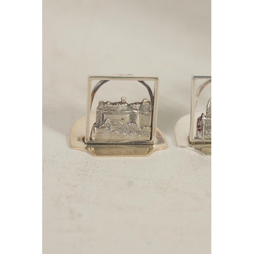 346 - A SET OF FOUR GEORGE V SILVER SCOTTISH CASTLE SCENE MENU HOLDERS of openwork design on solid shaped ... 