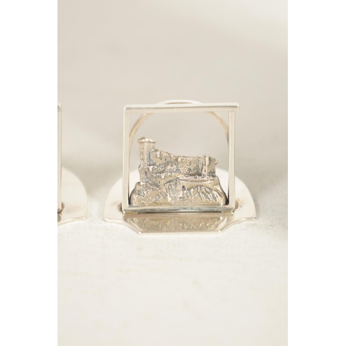 346 - A SET OF FOUR GEORGE V SILVER SCOTTISH CASTLE SCENE MENU HOLDERS of openwork design on solid shaped ... 