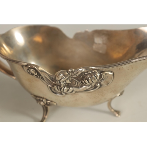 354 - A GEORGE V LARGE SILVER SAUCE BOAT with leaf capped double scroll handle, feather edged border and s... 