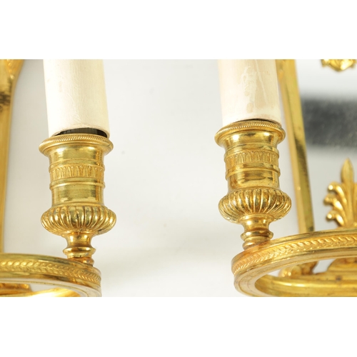 428 - A PAIR OF ORMOLU REGENCY STYLE TWO BRANCH WALL LIGHTS with tapering mirrored backs and ringed light ... 