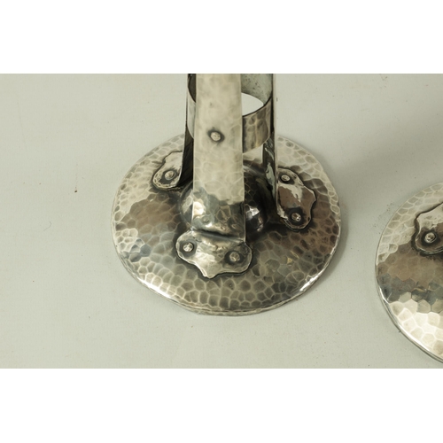 431 - A PAIR OF ARTS AND CRAFTS PLANISHED SILVERED COPPER STYLISED CANDLESTICKS of tapering form with rive... 