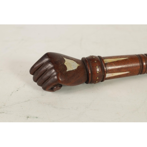 451 - A 19TH CENTURY MAHOGANY AND MOTHER OF PEARL INALID RIDING CROP with fist shaped handle and tapering ... 