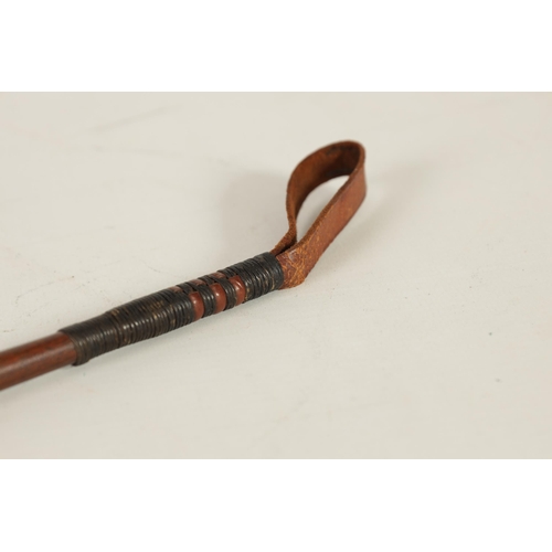 451 - A 19TH CENTURY MAHOGANY AND MOTHER OF PEARL INALID RIDING CROP with fist shaped handle and tapering ... 