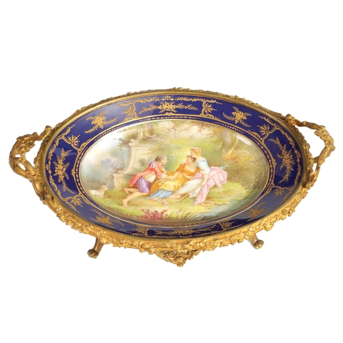 55 - A LATE 19TH CENTURY SERVES STYLE OVAL ORMOLU MOUNTED CENTREPIECE with a painted classical figure sce... 