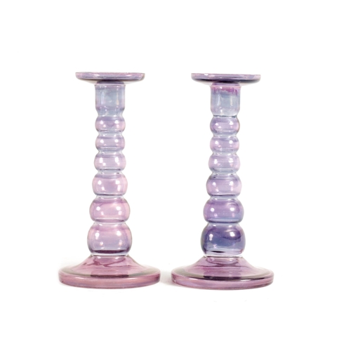 8 - A PAIR OF EARLY 20TH CENTURY IRIDESCENT AUBERGINE GLASS CANDLESTICKS with bobbin type stems and circ... 