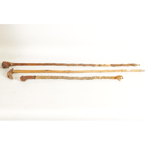 484 - TWO MASK HEAD CARVED WOOD WALKING STICKS AND A RIDING CROP of ethnic males on notched wood shafts, t... 