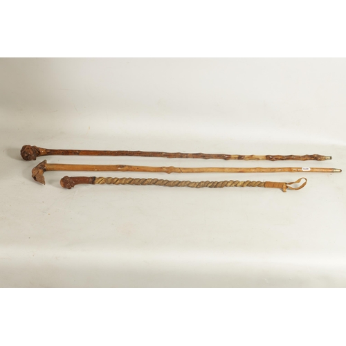 484 - TWO MASK HEAD CARVED WOOD WALKING STICKS AND A RIDING CROP of ethnic males on notched wood shafts, t... 