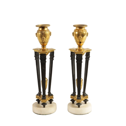 537 - A PAIR OF REGENCY FRENCH EMPIRE BRONZE AND ORMOLU CANDLESTICKS with urn shaped tops above triform su... 