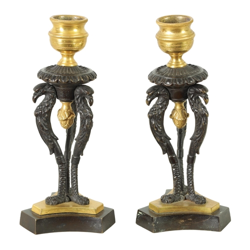 562 - A PAIR OF FRENCH EMPIRE BRONZE AND ORMOLU CANDLESTICKS with griffin mounts and triform pedestal base... 